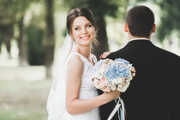 結婚式の日には花束を持って公園を歩く幸せなスタイリッシュな新婚夫婦 — ストック写真