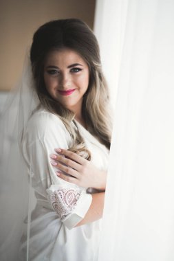 Cüppeli muhteşem gelin bir odada düğün töreni için poz veriyor ve hazırlanıyor.