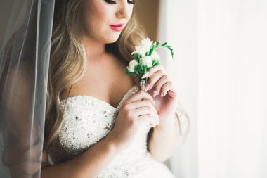 Cüppeli muhteşem gelin bir odada düğün töreni için poz veriyor ve hazırlanıyor.