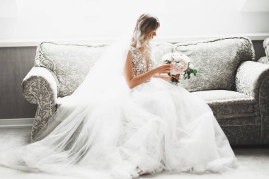 Çekici gelinin portresi, uzun saçlı, büyük buketli poz veren..