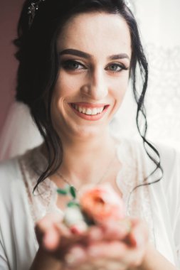 Cüppeli muhteşem gelin bir odada düğün töreni için poz veriyor ve hazırlanıyor..