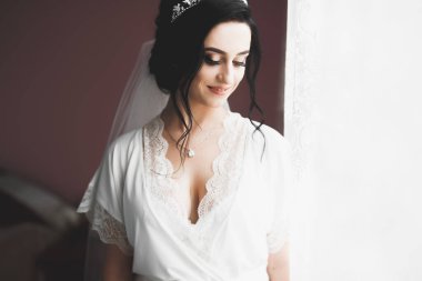 Cüppeli muhteşem gelin bir odada düğün töreni için poz veriyor ve hazırlanıyor..