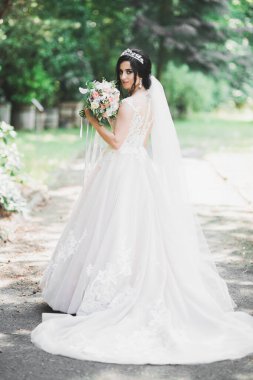 Çekici gelinin portresi, uzun saçlı, büyük buketli poz veren..