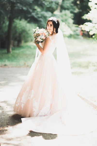 美しいですブルネット花嫁でエレガントな白いドレス保持花束ポーズきちんとした木 — ストック写真