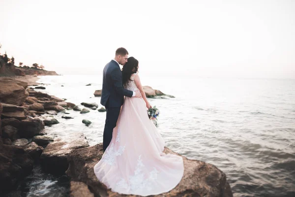 エレガントなスタイリッシュな幸せな結婚式のカップル 海と空の背景に豪華な新郎 — ストック写真