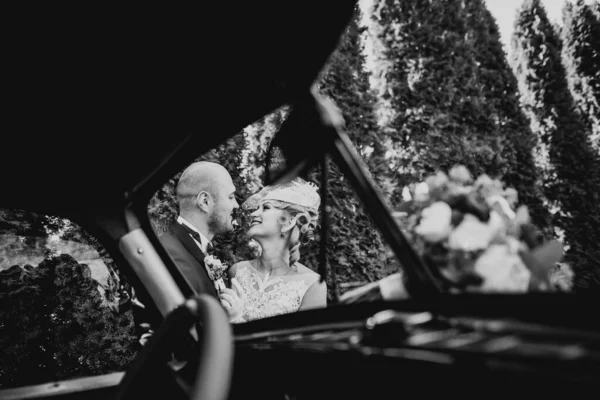 幸せな新婚者のカップル 男と妻のスタイリッシュなレトロな車の近くにキス — ストック写真