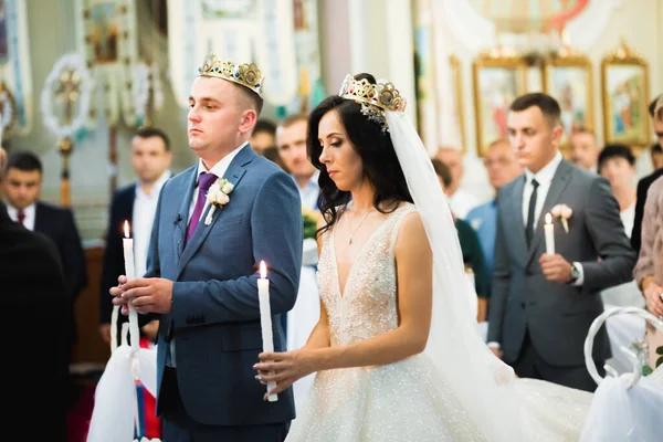 Bride and groom holding candles in church.