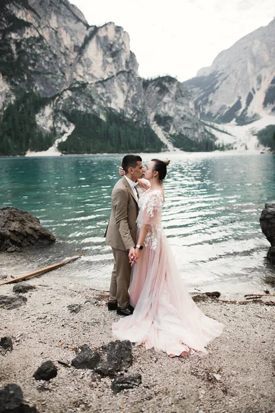 Young couple near lake Karersee, Italy. Holding hands at the stone at lake.