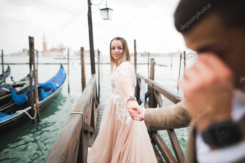 Wedding couple staying on a bridge near the canal with gondolas in Venice, Italy. Follow me.