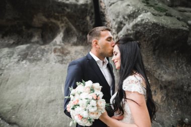 Güzel, genç bir çift ellerinde çiçeklerle poz veriyorlar..