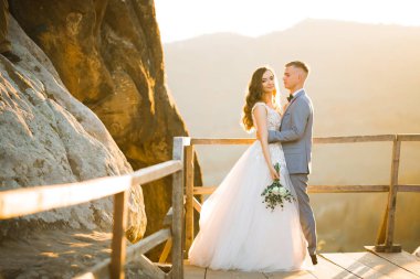 Doğadaki düğün çifti birbirine sarılıyor. Beyaz elbiseli güzel bir kız. Takım elbiseli adam.