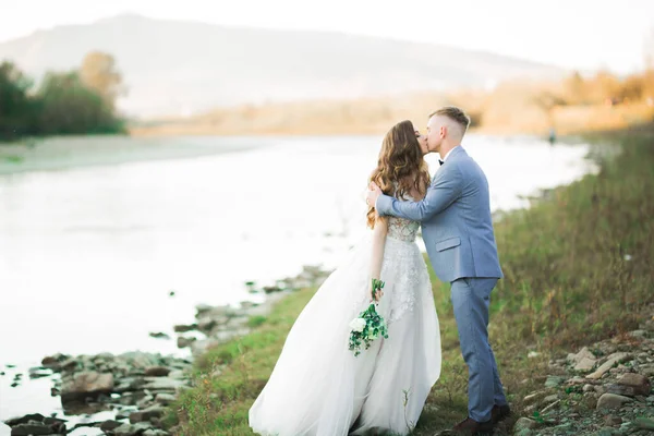 美しい結婚式のカップルのキスと石と山の川の岸の近くに抱擁 — ストック写真