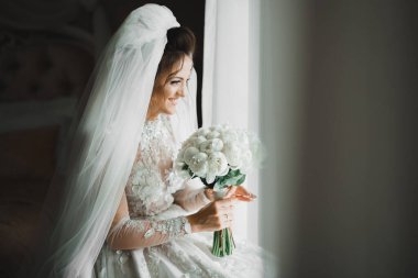 Lüks bir gelin, bir kız buketle poz veriyor ve gülümsüyor..