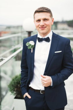 Yaka çiçeğiyle poz veren mutlu yakışıklı damat..