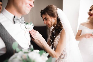 Gelin, damat ceketine yeşil yapraklı beyaz yaka çiçeğini iğneledi..