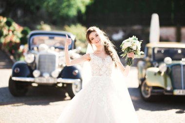 Lüks bir gelin, bir kız buketle poz veriyor ve gülümsüyor..