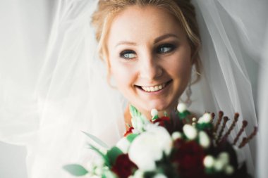 Zarif beyaz elbiseli güzel gelin elinde bir buket çiçek tutuyor..