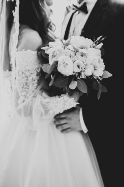 Güzel, genç bir çift ellerinde çiçeklerle poz veriyorlar..