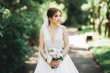 Çekici gelinin portresi, uzun saçlı, büyük buketli poz veren..