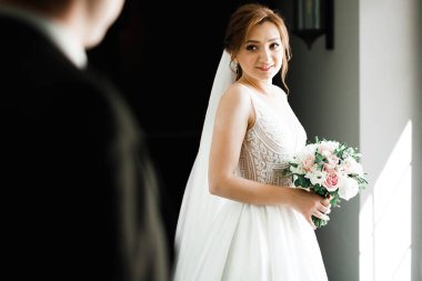 Çekici gelinin portresi, uzun saçlı, büyük buketli poz veren..