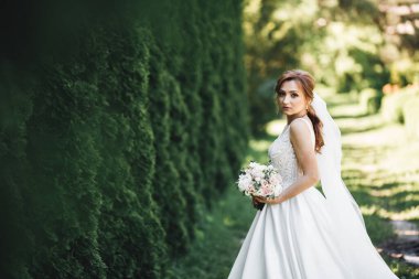 Çekici gelinin portresi, uzun saçlı, büyük buketli poz veren..