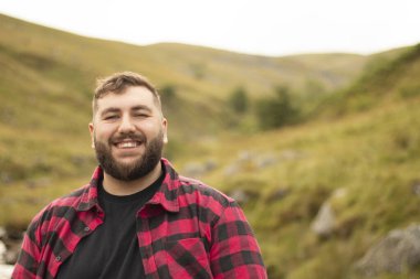 plus size male smiling into the camera while out on a travel adventure.
