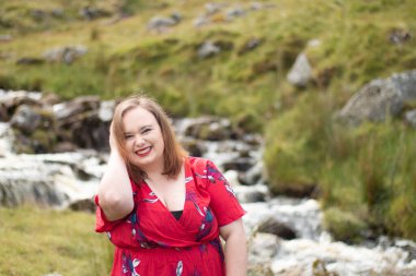 Plus size woman with brunette hair, wearing a red dress while on a travel adventure