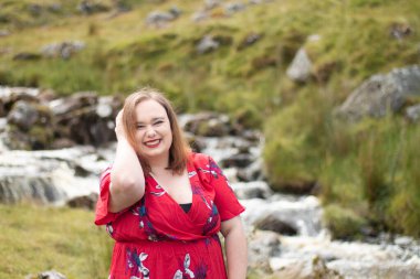 Plus size woman with brunette hair, wearing a red dress while on a travel adventure