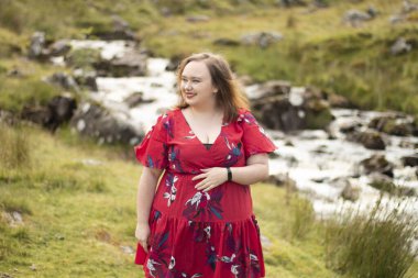 Plus size woman with brunette hair, wearing a red dress while on a travel adventure