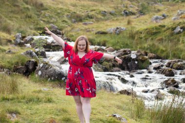 Plus size woman with brunette hair, wearing a red dress while on a travel adventure