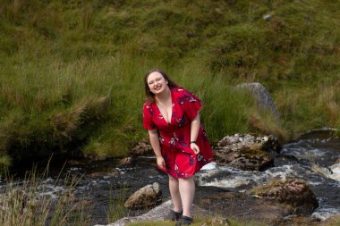 Plus size woman with brunette hair, wearing a red dress while on a travel adventure