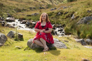 Plus size woman with brunette hair, wearing a red dress while on a travel adventure