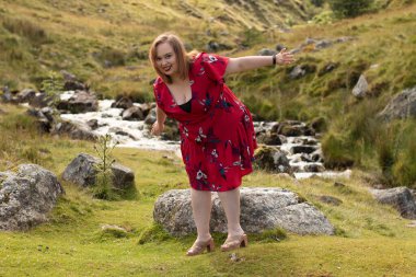 Plus size woman with brunette hair, wearing a red dress while on a travel adventure