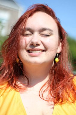 Ayrıca kadın portresi, şirin limon küpeler ve sarı bir elbise giyiyor.