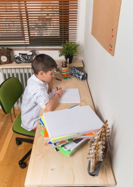 8 year old boy doing class homework in his home room.