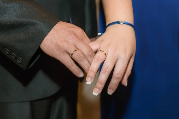 Gold rings displayed on the joined hands of the newlyweds.