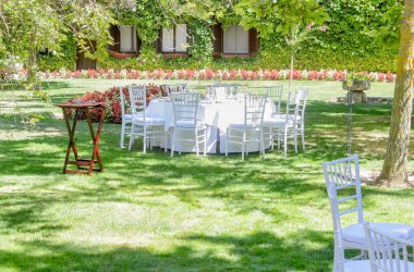 Güneşli bir günde bahçede beyaz masa ve sandalyeli mobilyalar..