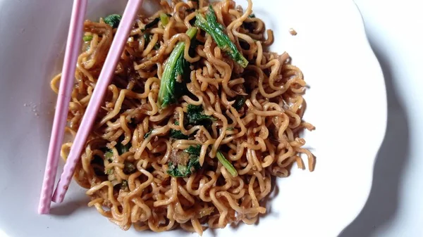 noodles cooked with a mixture of mustard greens with white background