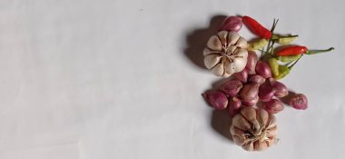 The ingredients for cooking are red onions, garlic and chilies with a white background