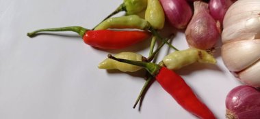 The ingredients for cooking are red onions, garlic and chilies with a white background