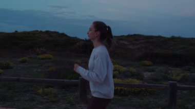 Güzel bir kız akşamleyin yolda koşar. Yüksek kalite 4k görüntü.