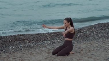 Güzel bir kız plajda spor yapıyor. Denizin arka planında sağlıklı yaşam tarzı ve zindelik. İspanya 'nın Akdeniz kıyısında uzanıyor. Yüksek kalite 4K görüntü. Yavaş çekim. 