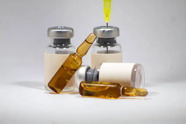 Empty medicine ampoules, vials and needles used for medical treatment, isolated white background, selective focus, noise effect