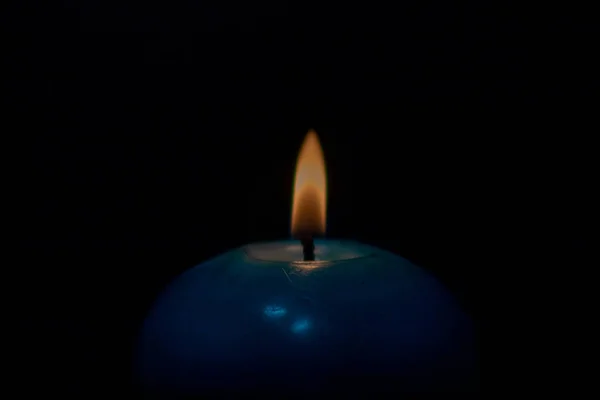 Candle flame and a blue candle on isolated black background