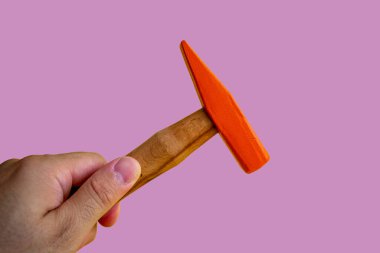 Hand held wooden handle hammer and orange head, isolated purple background, straight peen hammer, selective focus
