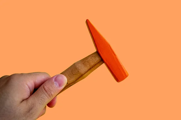 Hand held wooden handle hammer and orange head, isolated orange background, straight peen hammer, selective focus