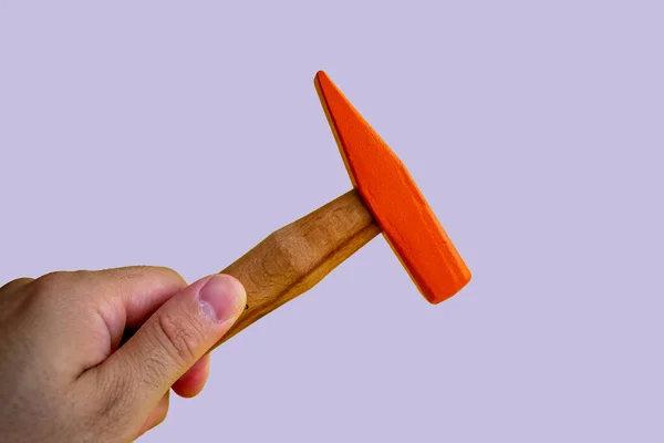 Hand held wooden handle hammer and orange head, isolated blue background, straight peen hammer, selective focus