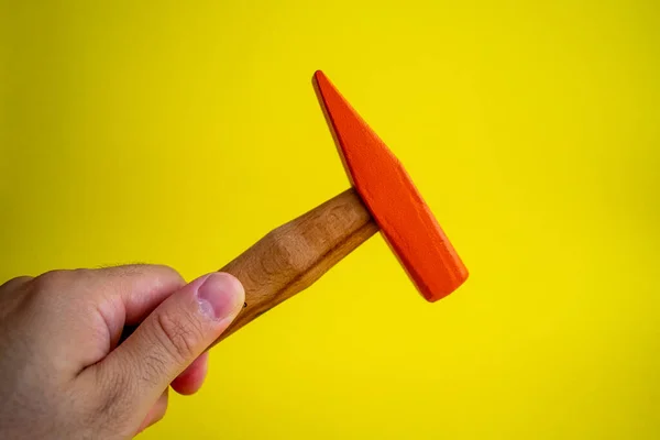 Hand held wooden handle hammer and orange head, isolated yellow background, straight peen hammer, selective focus