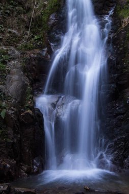Inegol, Bursa, Türkiye - Eylül 2022: Oylat Şelalesi, ormandaki güzel bir şelalenin uzun pozlu fotoğrafları, insan oturma silueti, seçici odaklanma