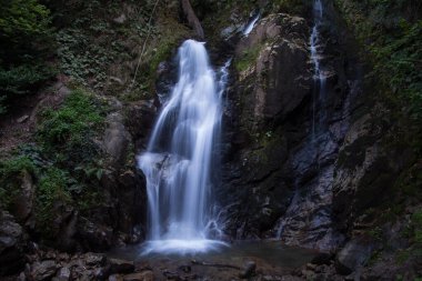 Inegol, Bursa, Türkiye - Eylül 2022: Oylat Şelalesi, ormandaki güzel bir şelalenin uzun pozlu fotoğrafları, insan oturma silueti, seçici odaklanma